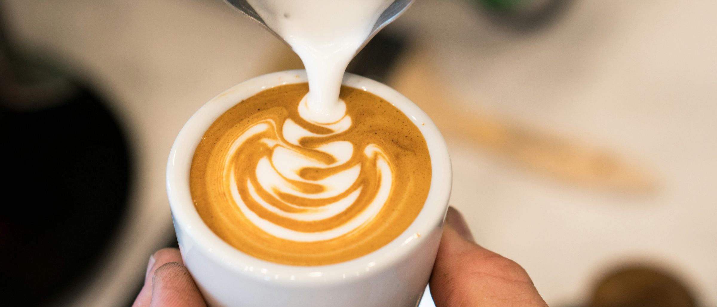 Barista pouring latte art on a cappuccino