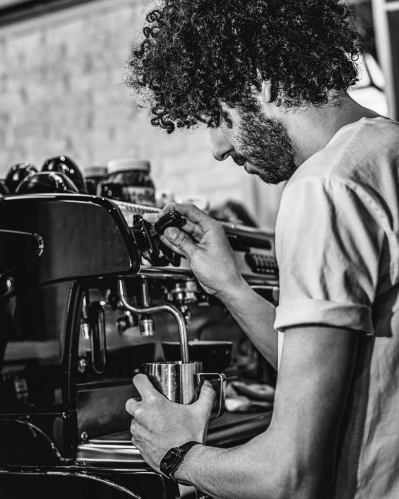 Espresso makinesinde süt köpürten barista