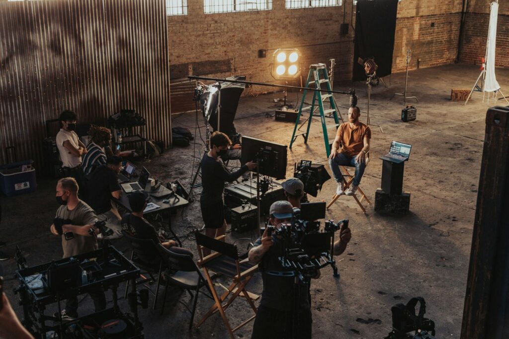 Film crew working with lighting and camera equipment in a studio