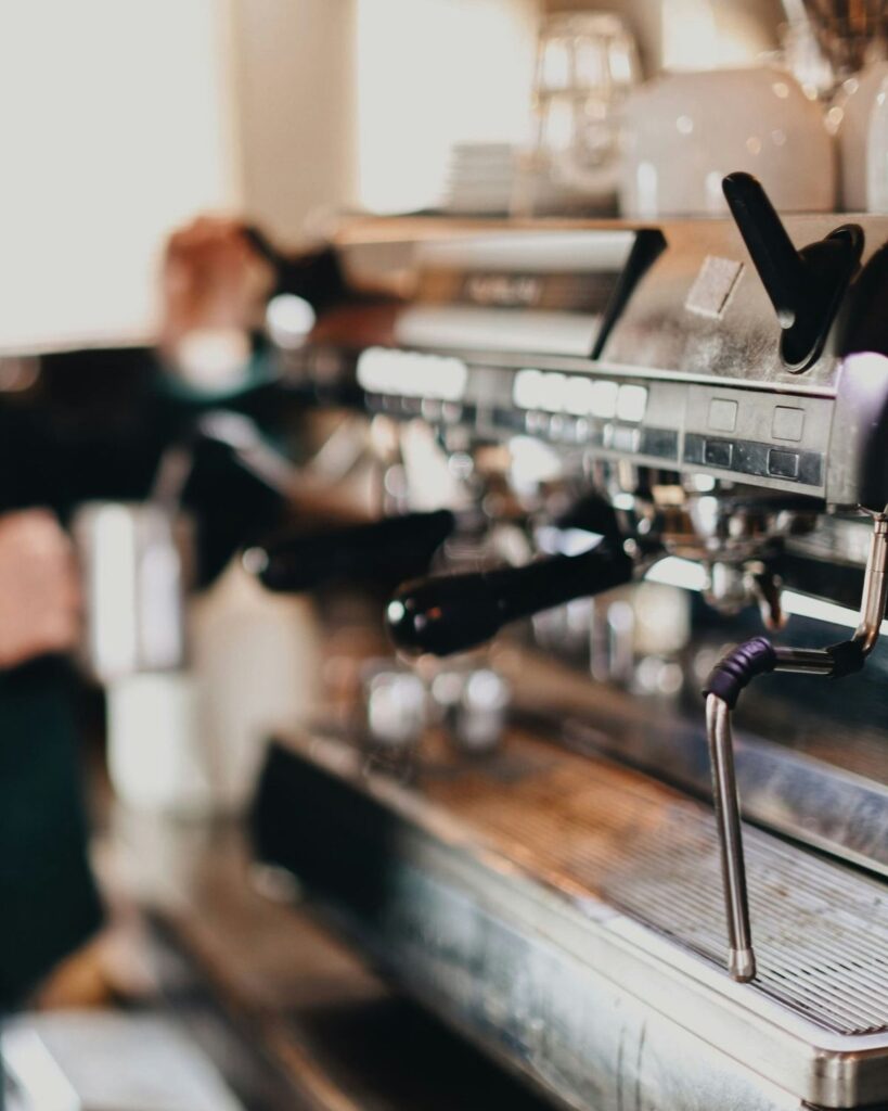 Yoğun servis sırasında çift gruplu espresso makinesinde çalışan barista