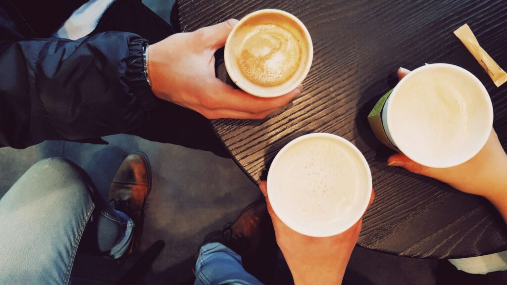 Katılımcıların elinde latte ve cappuccino dolu kâğıt bardaklar