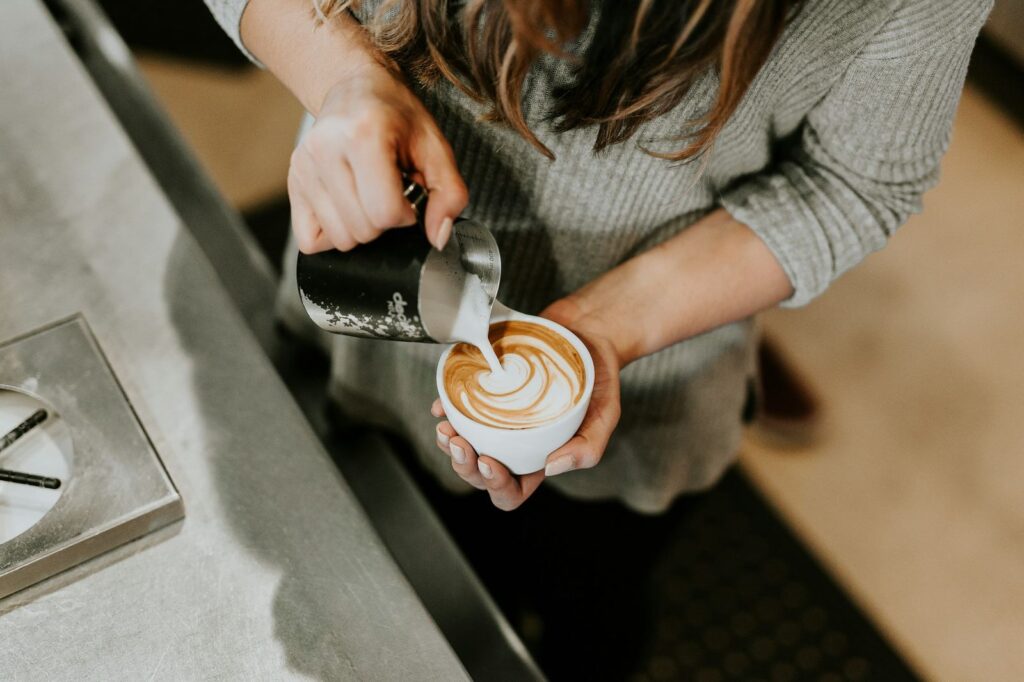 Barista sütü cappuccino fincanına dökerek latte art yapıyor